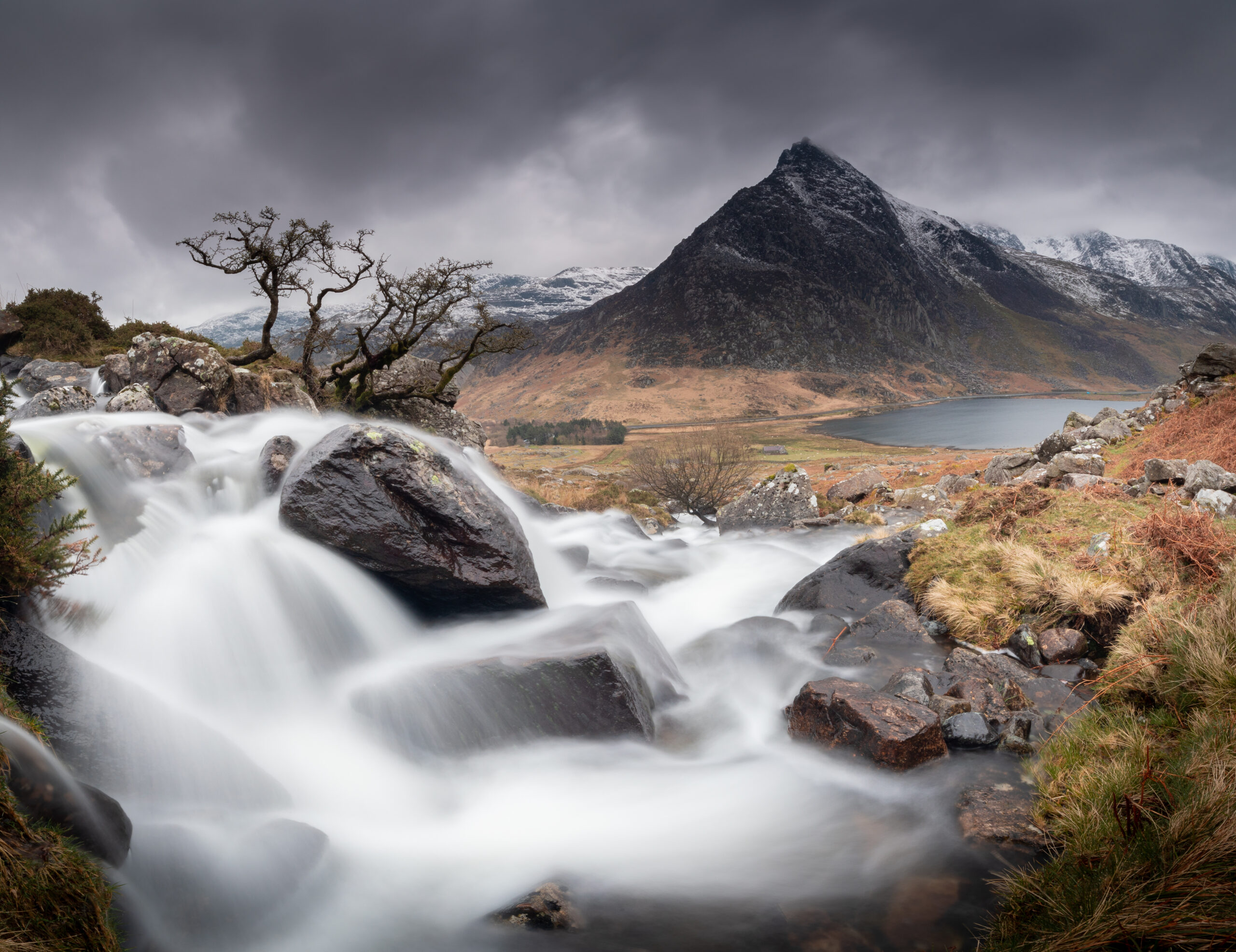 a river flowing over rocks with mountains in the background